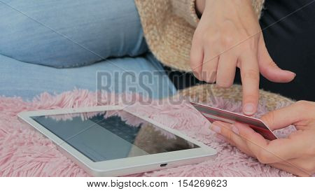 Young woman buying goods from the internet and entering number security code from credit card on digital tablet. Online, technology and internet concept.