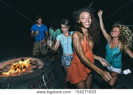 Group of friends making party on the beach with fire and music