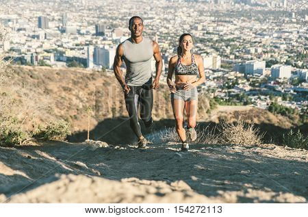 Couple of athlete running in the canyon. Los angeles city in the background