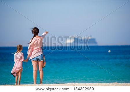 Young beautiful mother and her adorable little daughter on white sunny beach