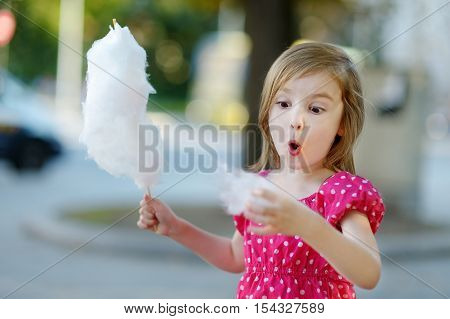 Adorable Little Girl Eating Candy-floss Outdoors