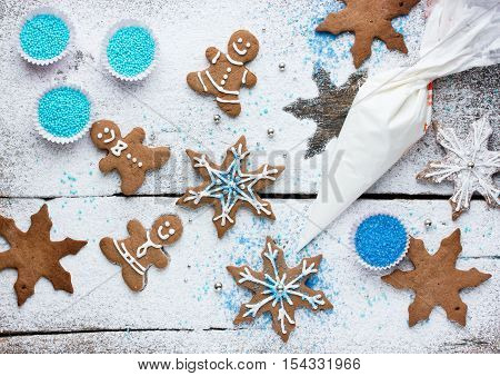 Decorating gingerbread man and snowflake Christmas cookie background Christmas treats for kids cooking process concept