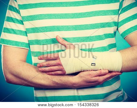Pain and injury concept. Young man holds bandaged hand. Injured part of body. Medicine and healthcare.