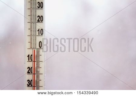 Outdoor thermometer with negative mark temperature on grey blurred background. Shallow depth of field. Focus on thermometer