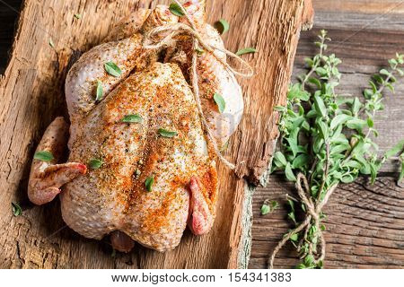 Raw chicken with herbs ready to roast on wooden table