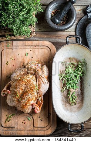 Preparing roast chicken with herbs on wooden table