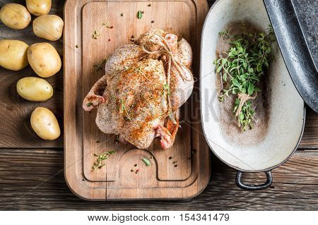 Preparation for roasting chicken with herbs on wooden table