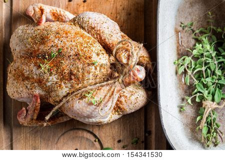 Chicken with herbs just before roasting on wooden table