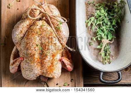 Chicken with herbs just before cooking on wooden table