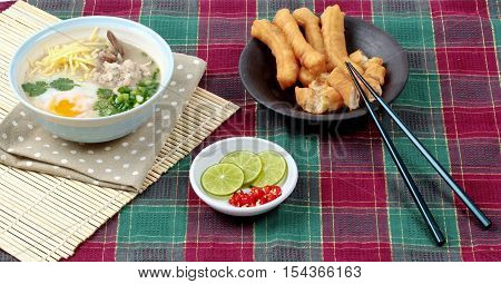 Rice porridge with mined pork and chicken lever served with side dish as Patongko (deep-fried dough stick) and spicy sour filling.