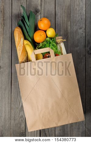Various food in paper bag on wooden background. Grocery shopping concept top view