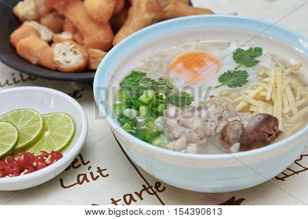 Close up of rice porridge with mined pork and chicken lever served with side dish as Patongko (deep-fried dough stick) and spicy sour filling.