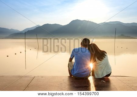 A couple on the wooden port at a lake on sunset