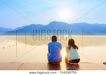 A couple on the wooden port at a lake on sunset
