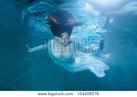 Fairy woman under the water she is wearing a white dress.