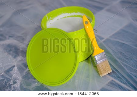 Yellow paint brush and green bucket on the floor ready for housework project and walls redecoration