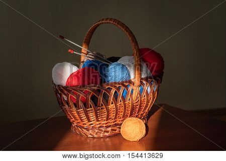 multicolored tangles lie to a basket with knitting needles and products