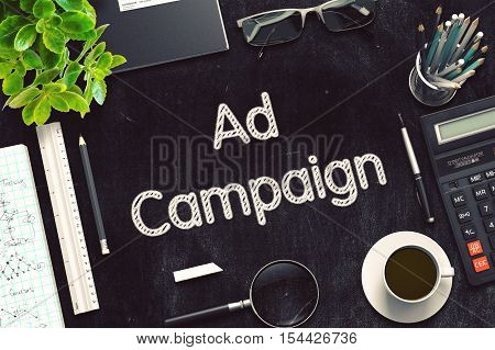 Ad Campaign Handwritten on Black Chalkboard. Top View of Black Office Desk with a Lot of Business and Office Supplies on It. 3d Rendering. Toned Image.