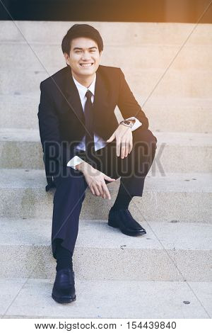 Portrait Of Smiling Young Handsome Businessman Sitting On The Stairs