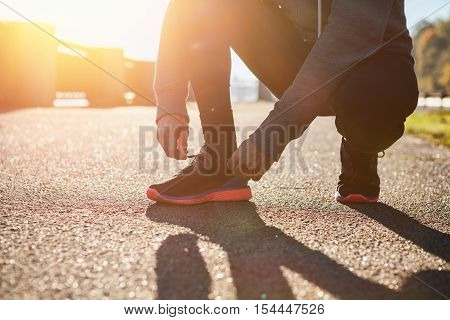 Man tying jogging shoes on sunset. Lifestyle concept