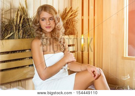 Young beautiful woman relaxing in the Finnish sauna wrapped in towel