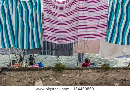 DHAKA BANGLADESH- JUNE 25 2016. Unidentified washerman wash their cloths in the river