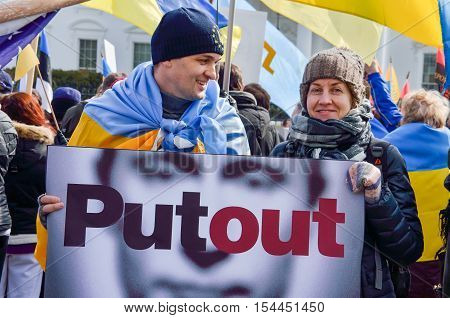 Washington DC, USA - March 6, 2014: Man and woman holding Vladimir Putin sign stating Putout during Ukrainian protest with flags by White House