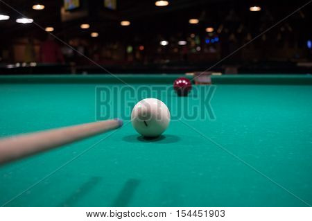 Russian billiards game in progress: player aims to shoot balls with cue