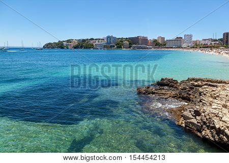 Rocky shore of Palmanova. Rocky shore of Palmanova on a sunny day. In the distance the crowded beach as well as many hotels and rest homes