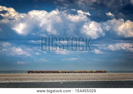 Several railroad hopper cars parked on rural tracks all by themselves on a hot Spring day. Few old carriages left alone on a railroad among beautiful nature. Blue sky and big white clouds surround train