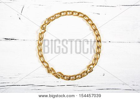 Brilliant gold baubles like christmas decoration. Yellow heart isolated on white wooden background.