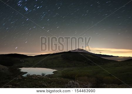 Lake Nebrodi Park and volcano Etna beneath stars trails, Sicily 