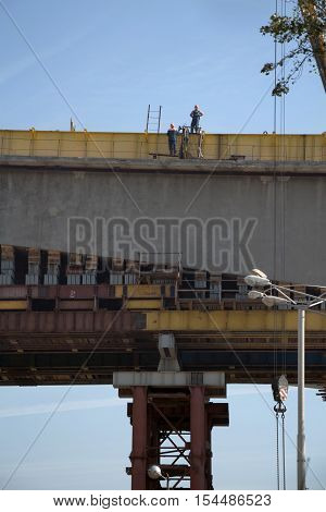 Two workers in workwear standing high on a bridge processing construction work