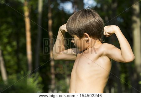 portrait of a boy in nature which shows his muscles