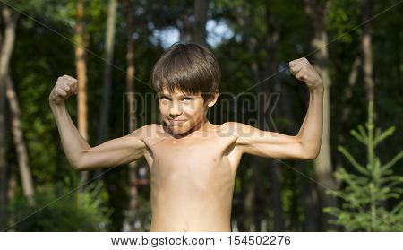 portrait of a boy in nature which shows his muscles