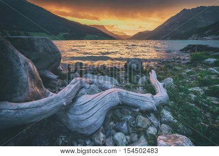 Beautiful view of the lake Resia. Dramatic sky and colorful sunset. Alps, Italy, Europe. Toned like Instagram filter