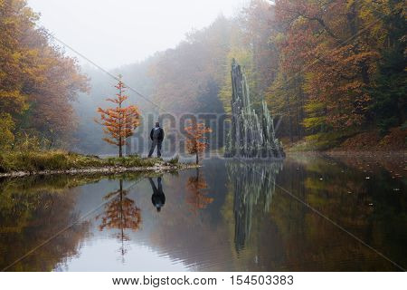 Traveler near Rakotzbruecke (Devil's bridge) in early morning mist, in autumn, Kromlau, Germany