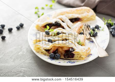 Puff pastry with apple and blueberry decorated with powdered sugar
