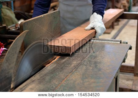 young worker while cutting wood on table saw