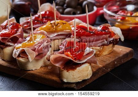 Spanish Tapas With Slices Jamon Serrano And Grilled Pepper. Also Olives, Salami, Pickled Onions, And