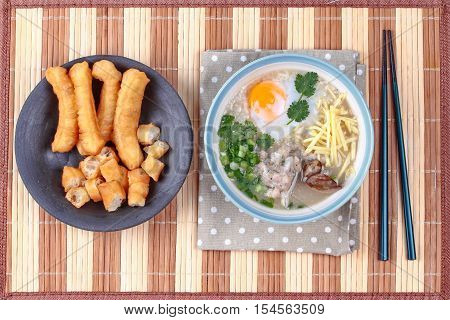 Rice porridge with mined pork and chicken lever served with side dish as Patongko (deep-fried dough stick) and spicy sour filling.