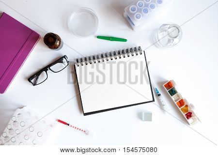 doctor workplace with blank open notebookat lab top view on white background