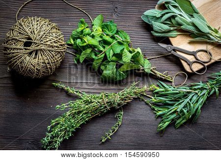bundle of sage and thyme, mint, estragon on wooden board top view.
