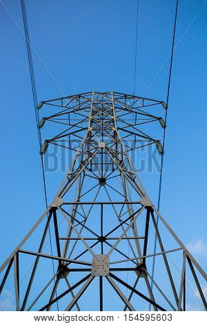 High voltage 110kV reliance power line tower front-bottom view on blue sky