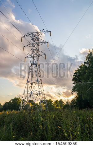 Power transmission tower 110kv on background greenery on a summer evening