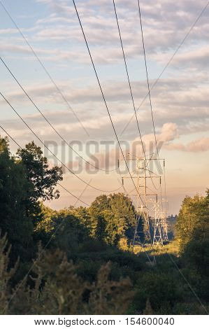 Power transmission tower 110kv on background greenery on a summer evening