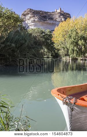 Alcala del Jucar Spain - October 29 2016: Jucar river boat of recreation in small lagoon in the central part of the town at the top of mountain limestone is situated castle of Almohad origin of the century XII take in Alcala of the Jucar Albacete province