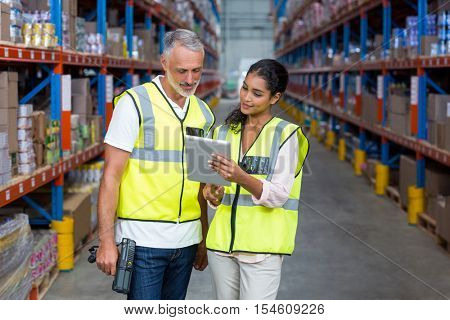 Warehouse workers discussing with digital tablet in the warehouse