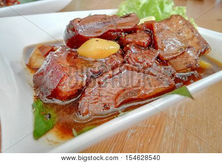 Close up picture of Thai food Stewed Pork Belly ( Moo Hong ) on white plate with brown wood table Popular local food in PhuketThailand
