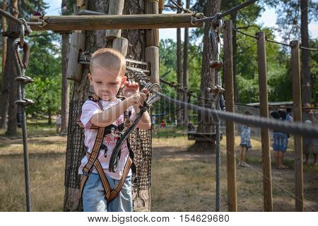 kid having a quest in the rope park. climing throgh rope bridge.